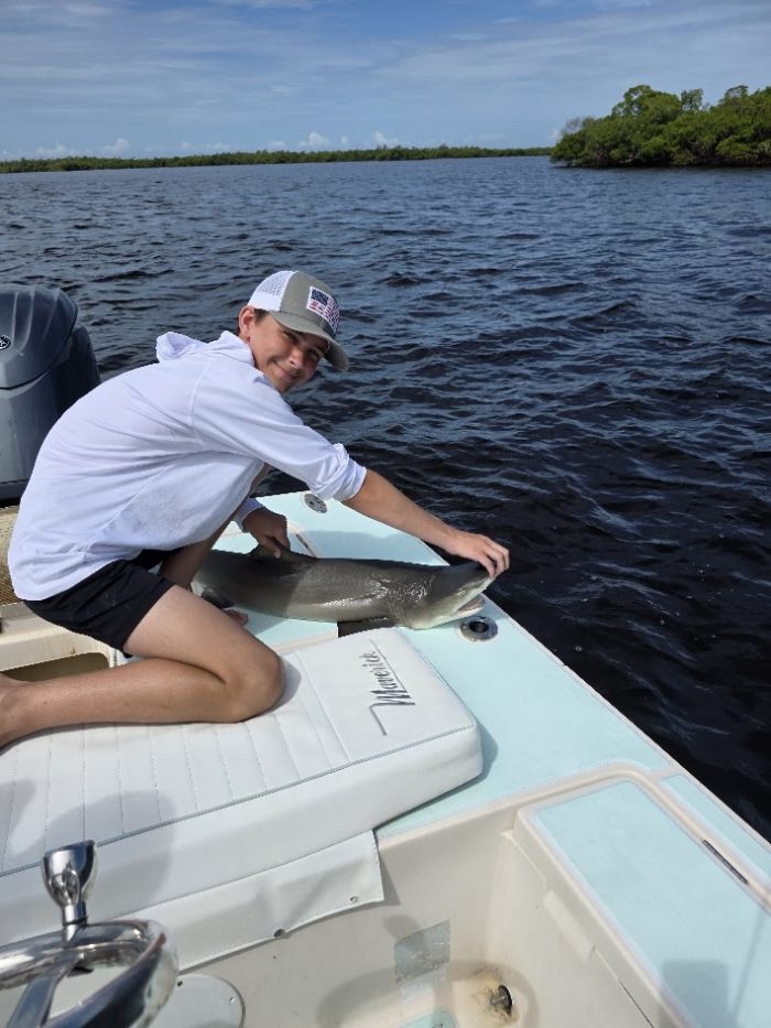 Mason holding a lemon shark on a fishing charter